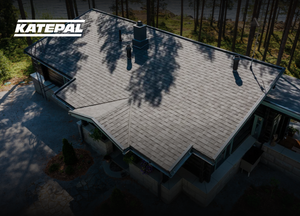 Dom so sivou šindľovou strechou obklopený stromami, pohľad zhora pri dennom svetle. Logo Katepal sa nachádza v ľavom hornom rohu obrázka.